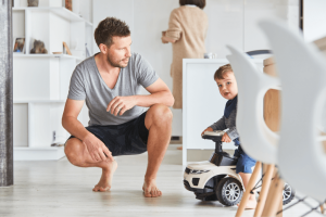 Vater mit Kind auf Spielzeugauto